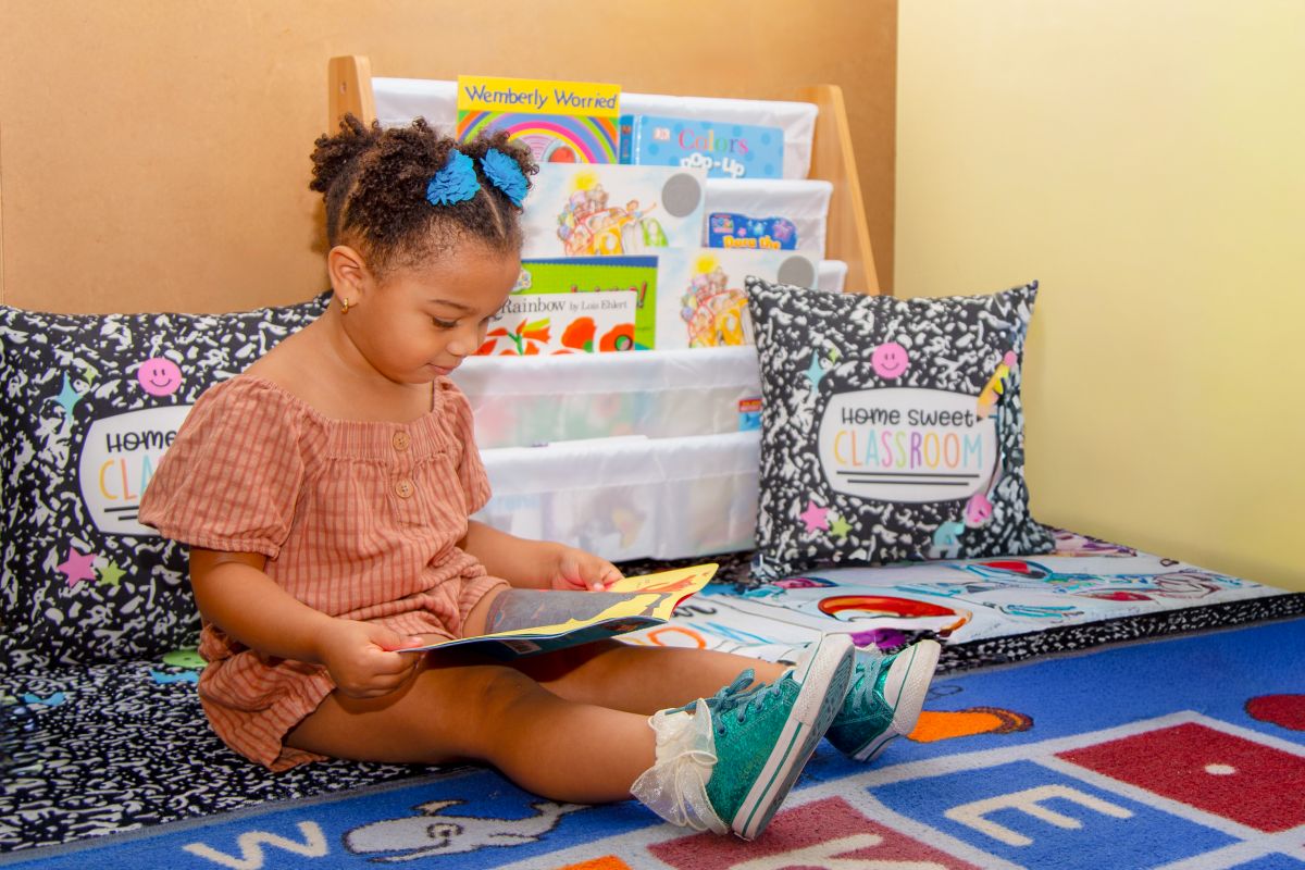 A toddler enjoying a book in the reading nook at MyPlace, Katy TX