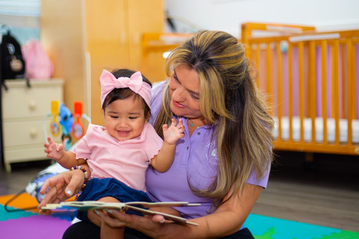 A teacher reading with a happy infant at MyPlace, Katy TX