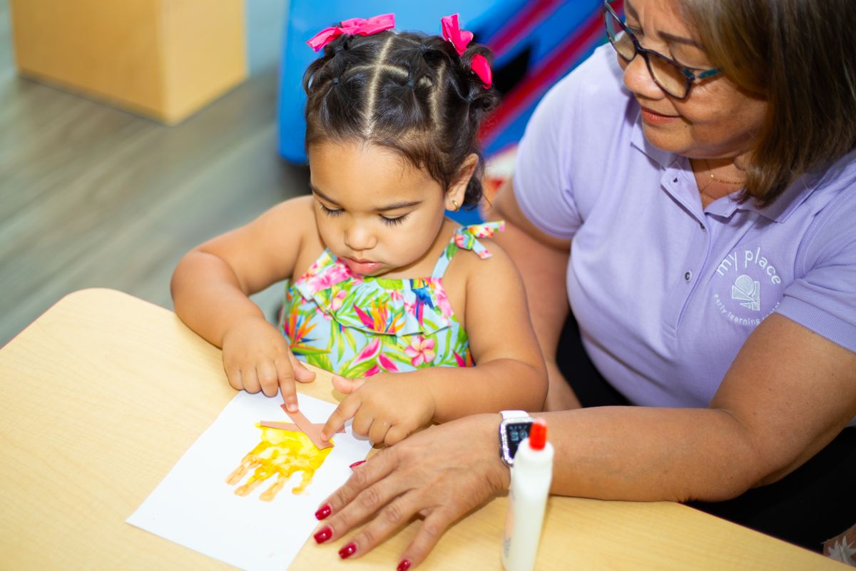 A Twos student painting with her teacher at MyPlace, Katy TX