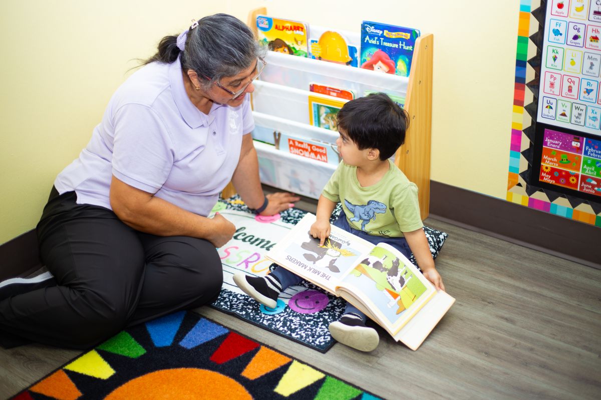 A toddler reading with his teacher at MyPlace, Katy TX