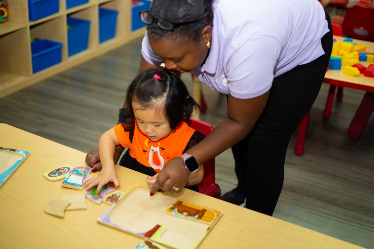 A teacher helping a preschooler with a puzzle at MyPlace, Katy TX